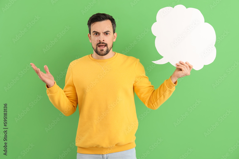 Angry young man with blank speech bubble on green background