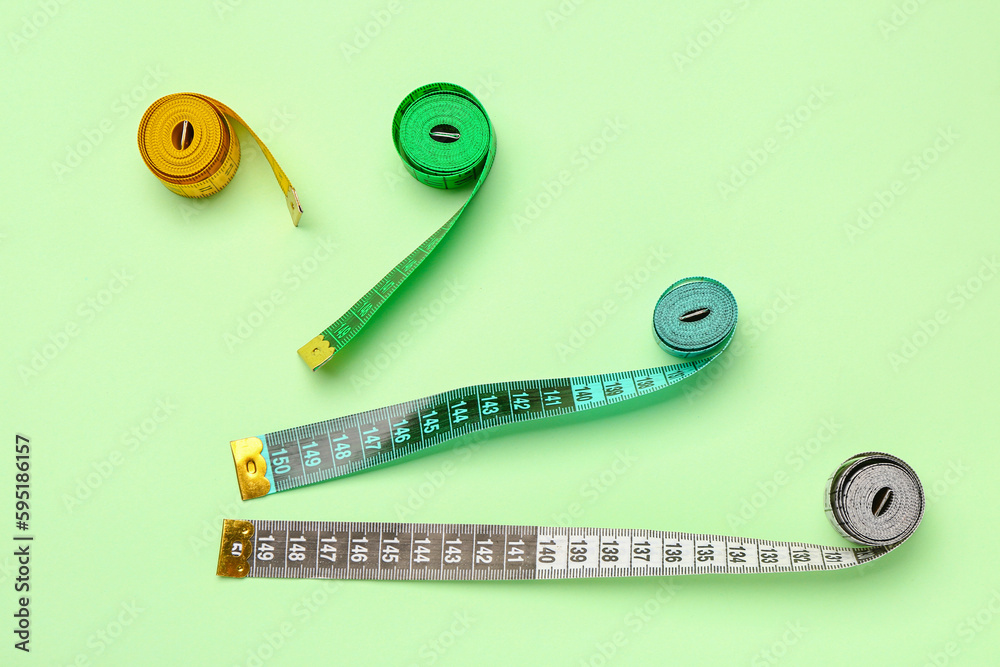 Colorful measuring tapes on green background