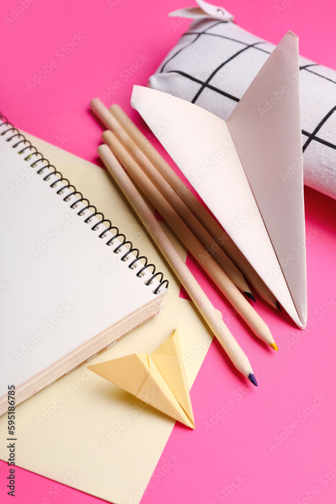 Composition with stationery supplies and paper planes on pink background