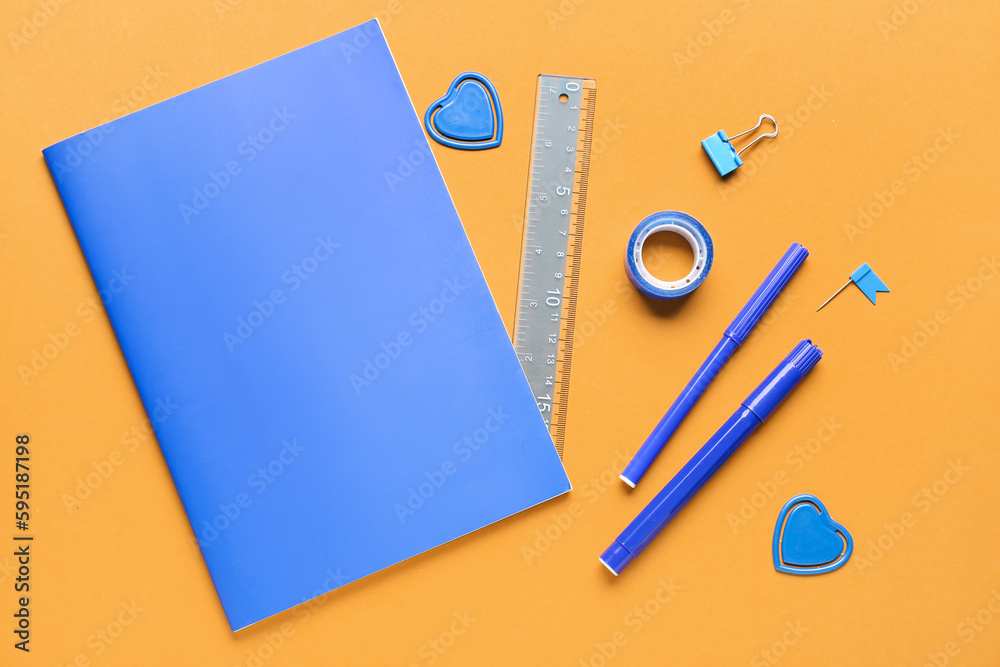 Notebook and stationery supplies on orange background