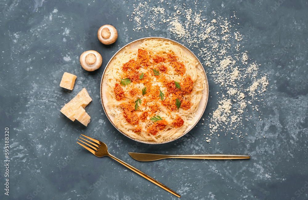 Plate of tasty Italian pasta with Parmesan cheese on blue background