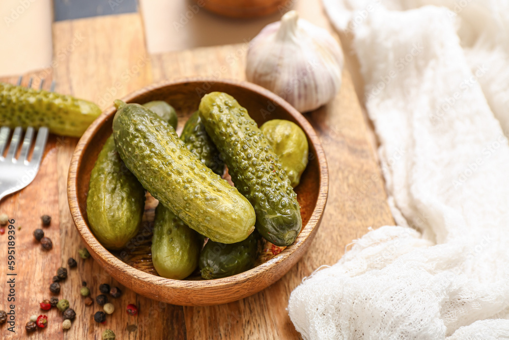 Bowl with tasty fermented cucumbers on beige background