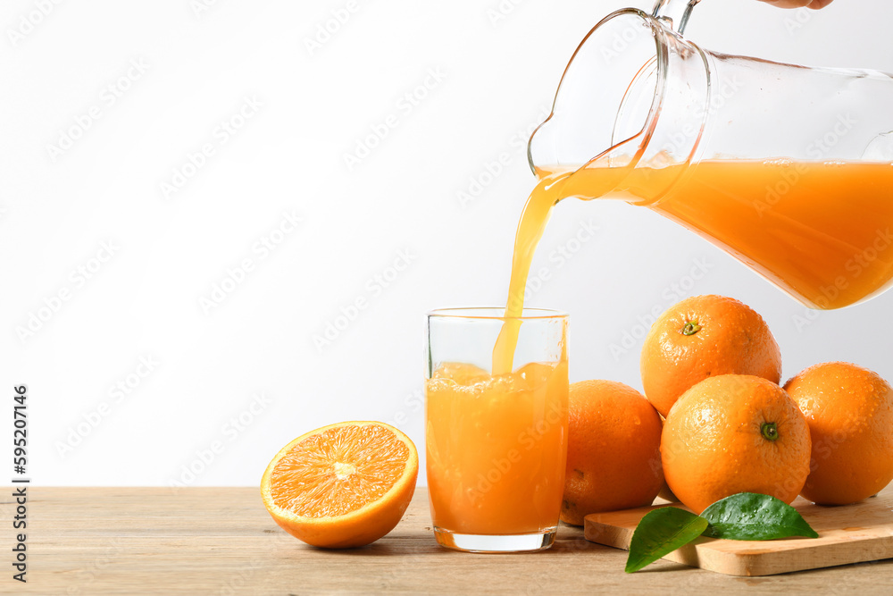 Pouring orange juice into the glass on wooden table.