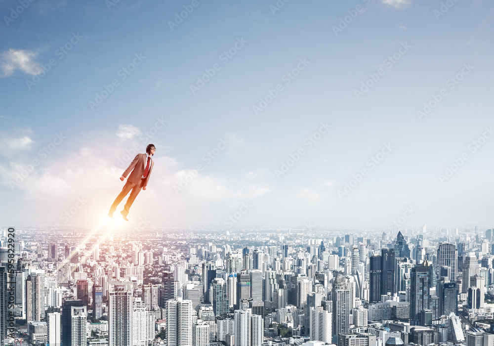 Businessman in suit and aviator hat flying in sky