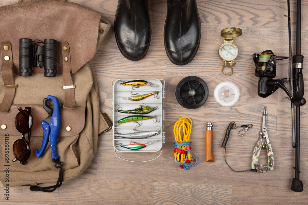 Fishing rod, tackles and other stuff for recreation activity on the wooden desk. Fishing season conc