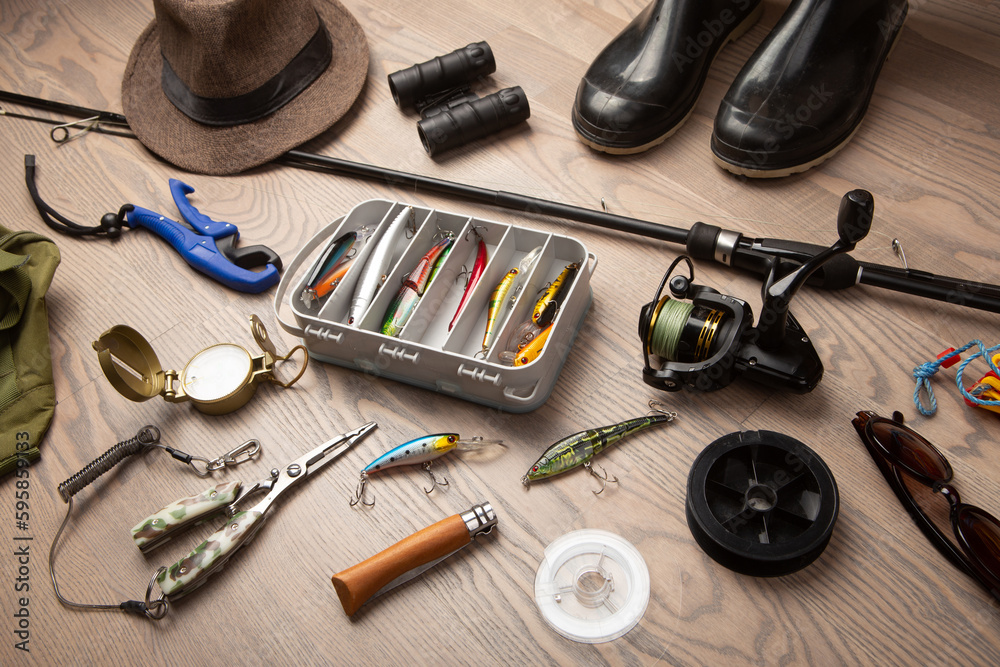 Fishing rod, tackles and other stuff for recreation activity on the wooden desk. Fishing season conc