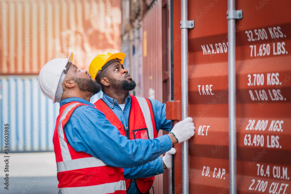 Portrait of Two African Engineer or foreman wears PPE checking container storage with cargo containe