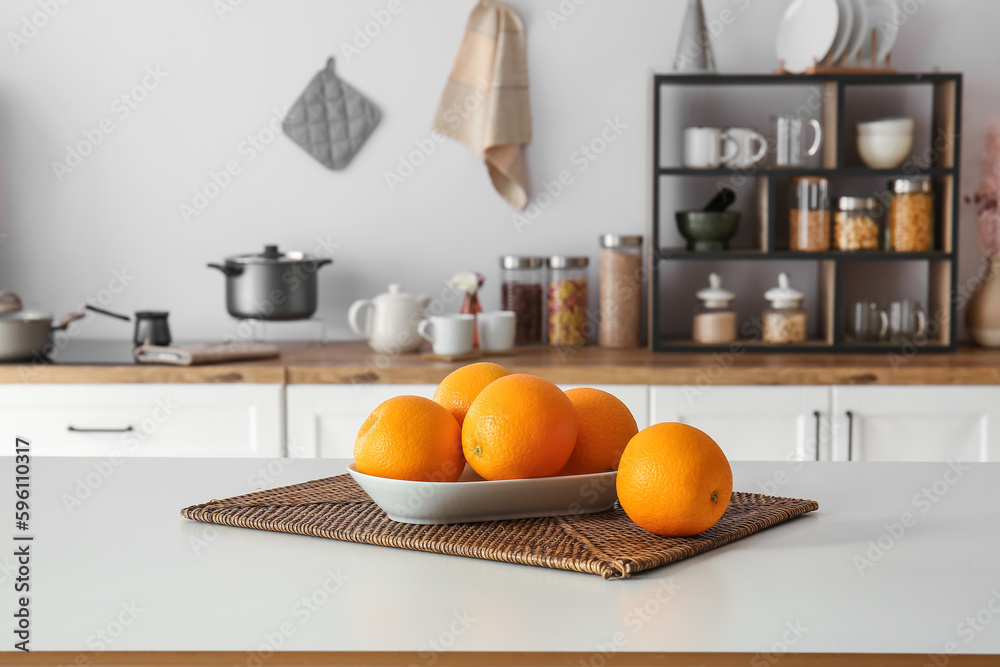 Plate with oranges on table in modern kitchen