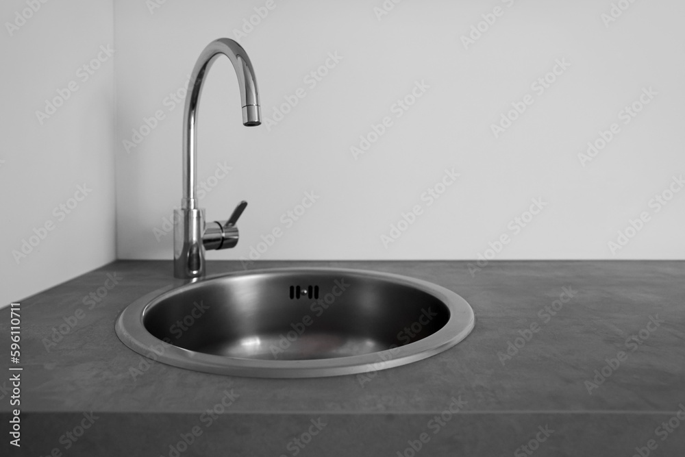 Silver sink on kitchen counter near light wall