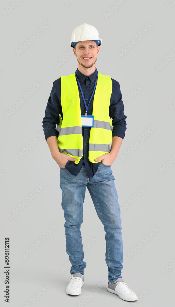 Male worker in vest and hardhat on grey background