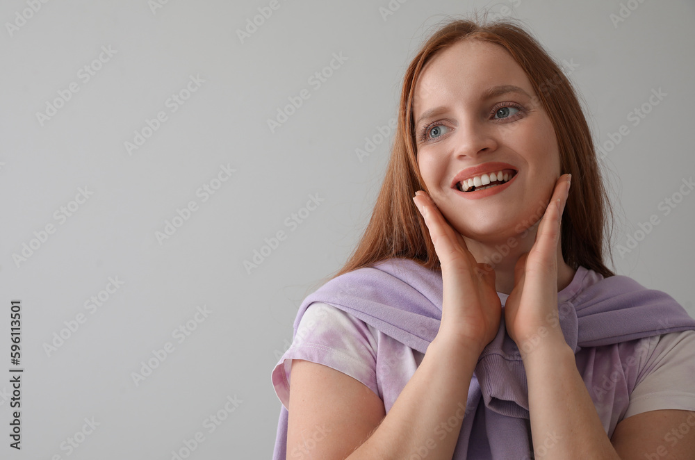 Beautiful redhead woman smiling on grey background, closeup