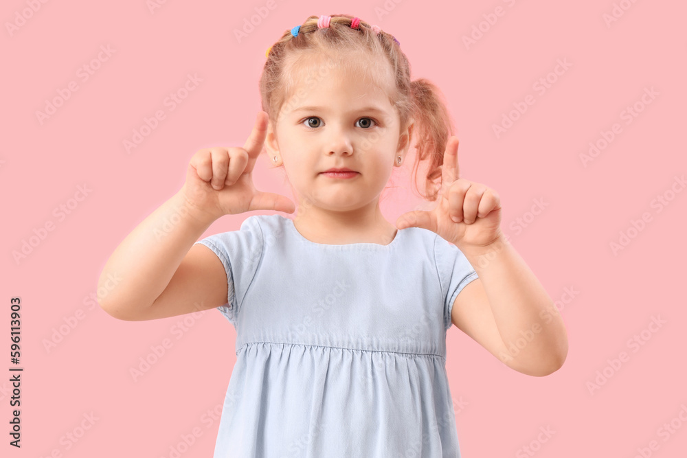 Funny little girl showing loser gesture on pink background