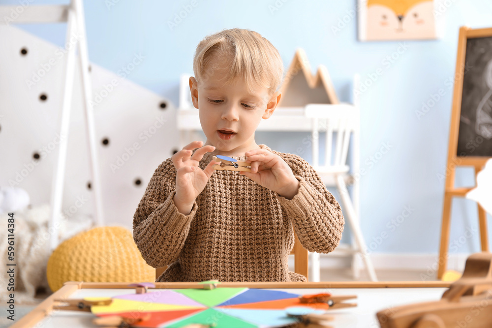 Cute little boy playing matching game with clothespins at home