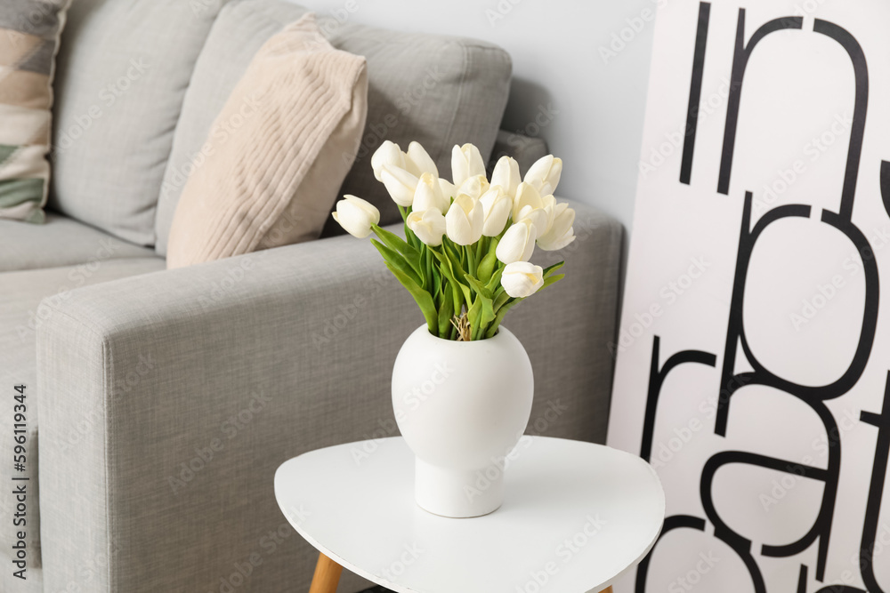 Vase with beautiful tulip flowers on table  near grey sofa