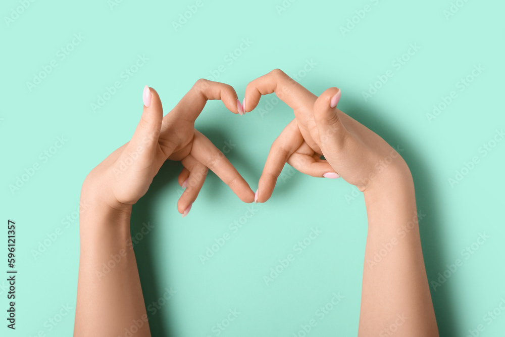 Woman making heart with her hands on green background