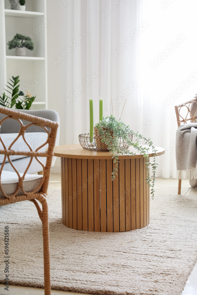 Coffee table with aroma candles and houseplant in bright living room