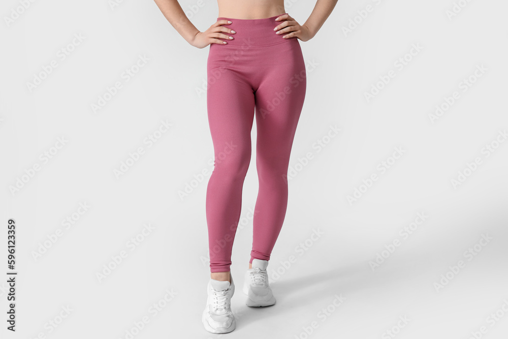 Sporty young woman in leggings on white background