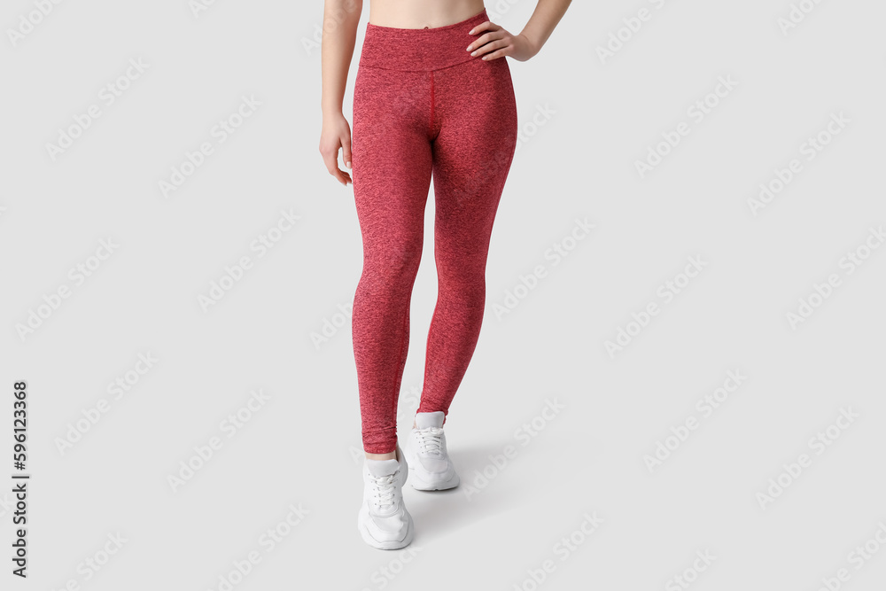 Sporty young woman in leggings on white background