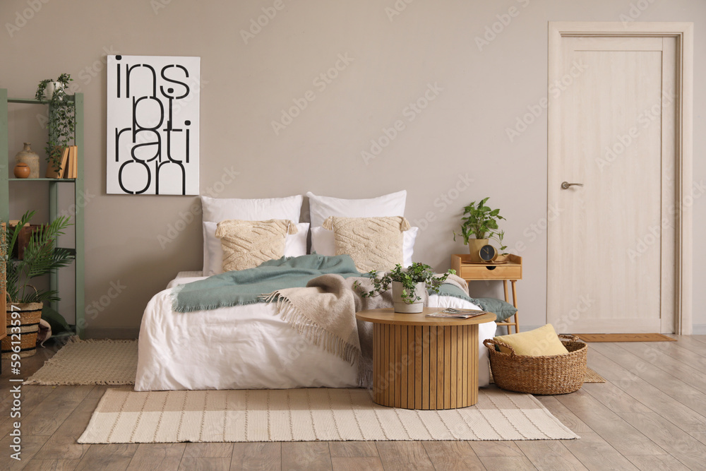 Interior of bedroom with cozy bed and houseplant on coffee table