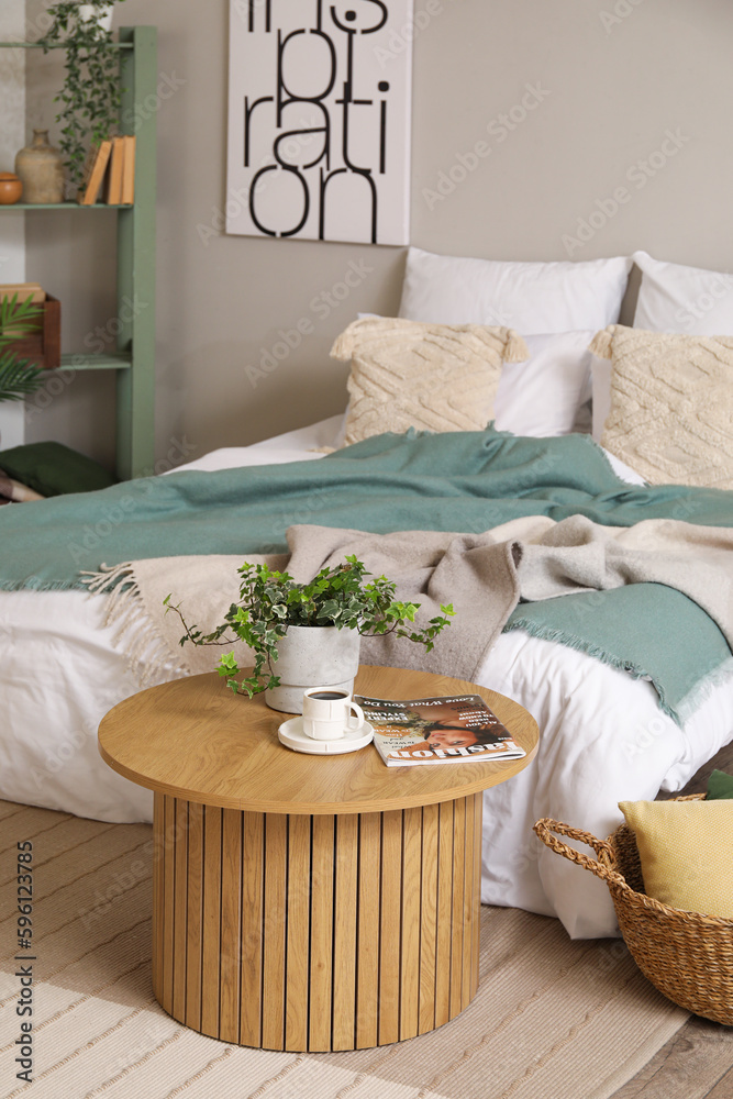 Interior of bedroom with cozy bed and houseplant on coffee table