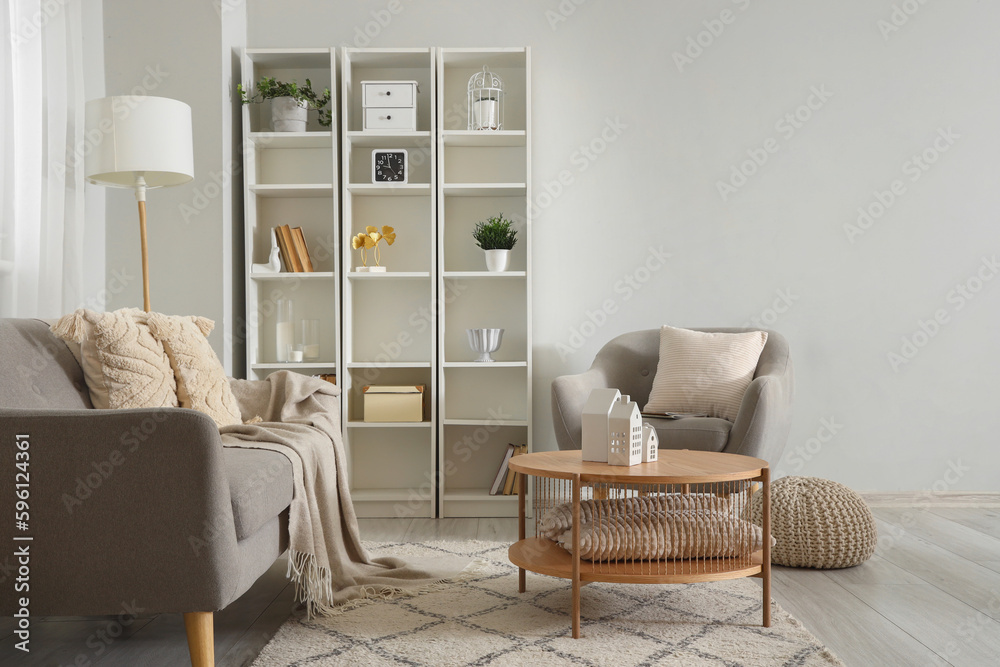 Interior of stylish living room with coffee table, grey armchair and cozy sofa