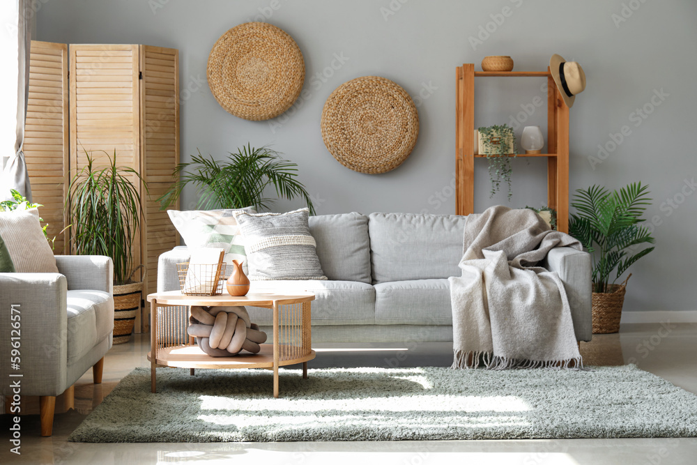 Interior of light living room with sofas, houseplants and table