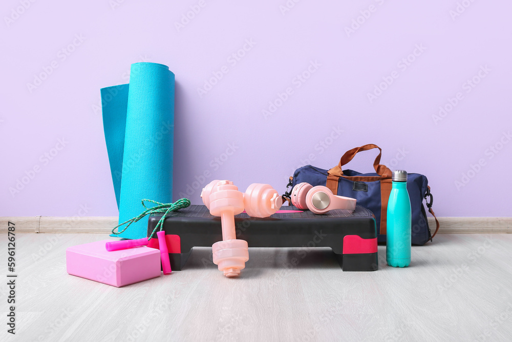 Sports equipment with headphones near lilac wall in gym