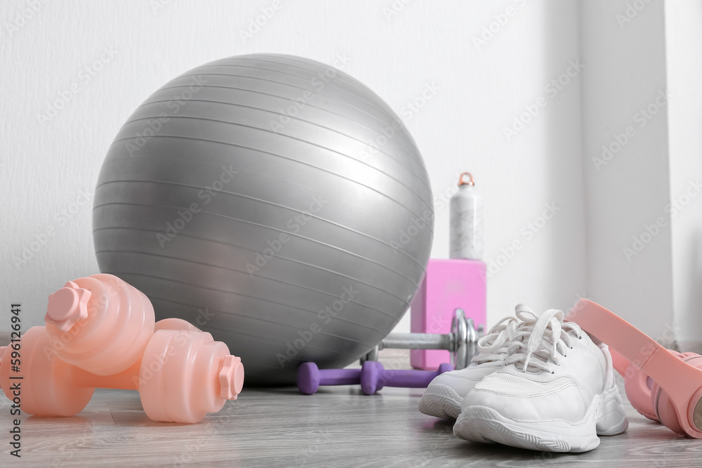 Sports equipment with sneakers and headphones near white wall in gym