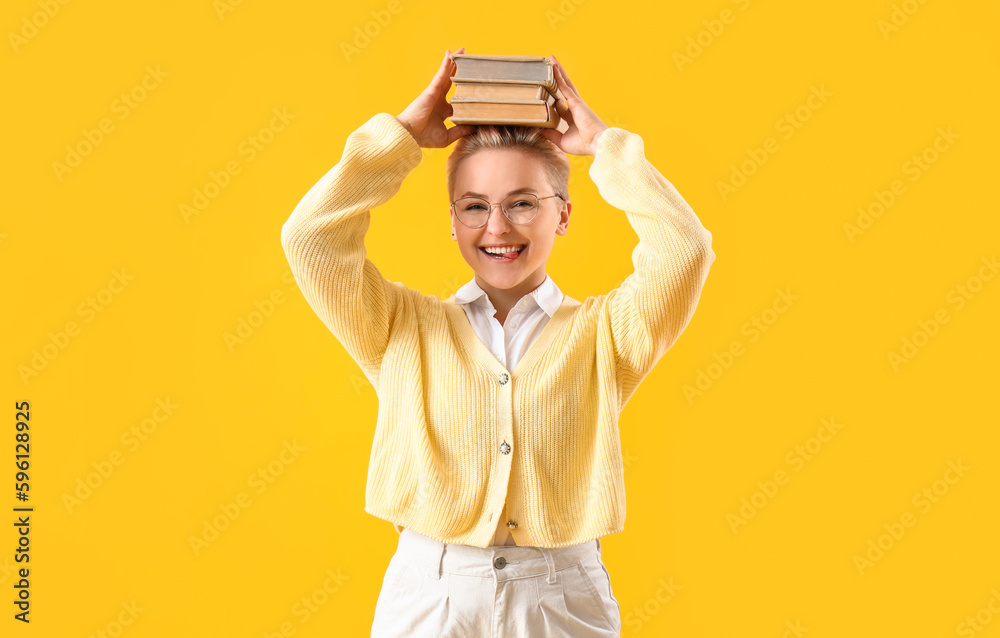 Female student with books on yellow background