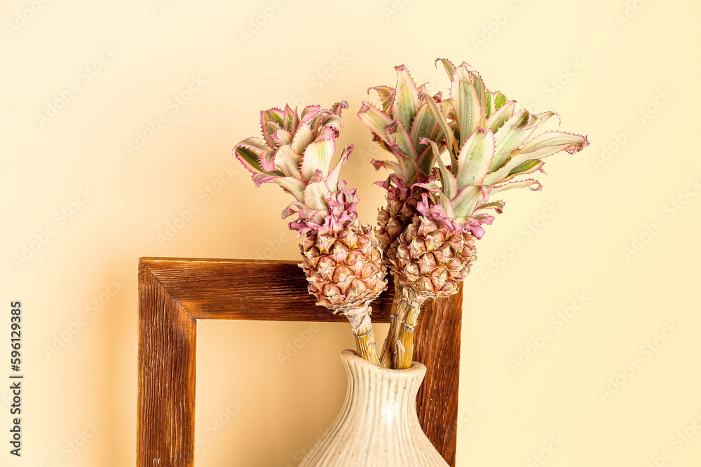 Vase with decorative pineapples and frame on beige background, closeup