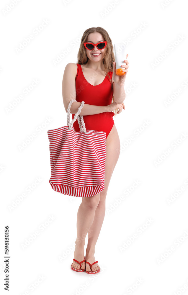 Beautiful young woman with sunscreen cream and beach bag on white background