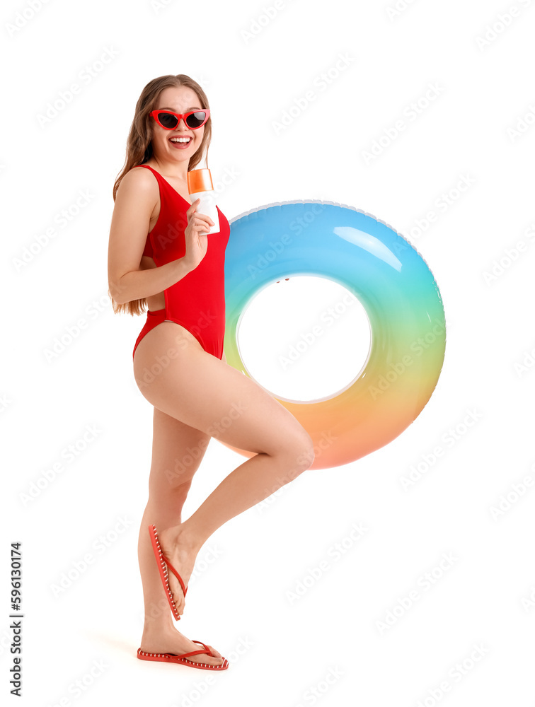 Beautiful young woman with sunscreen cream and inflatable ring on white background