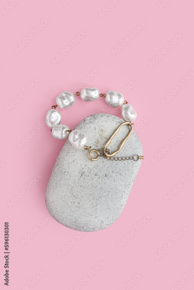 Stone with pearl bracelet on pink background