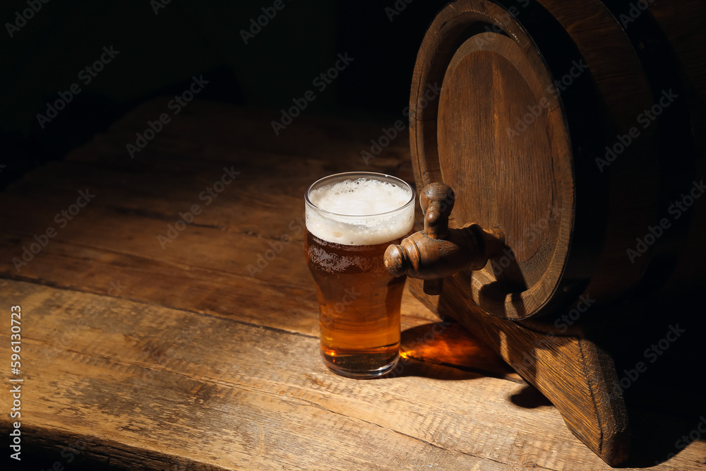 Wooden barrel and glass of cold beer on table