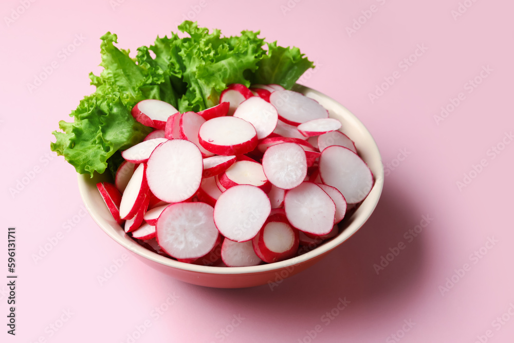 Bowl with sliced radish and lettuce on pink background