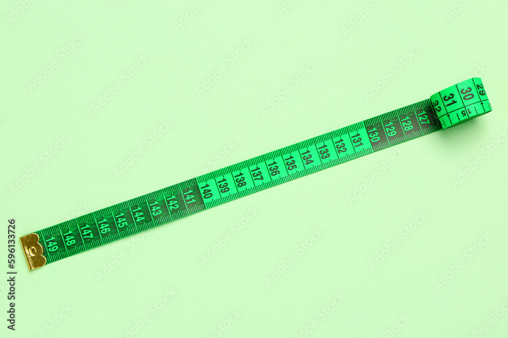 Green measuring tape on color background