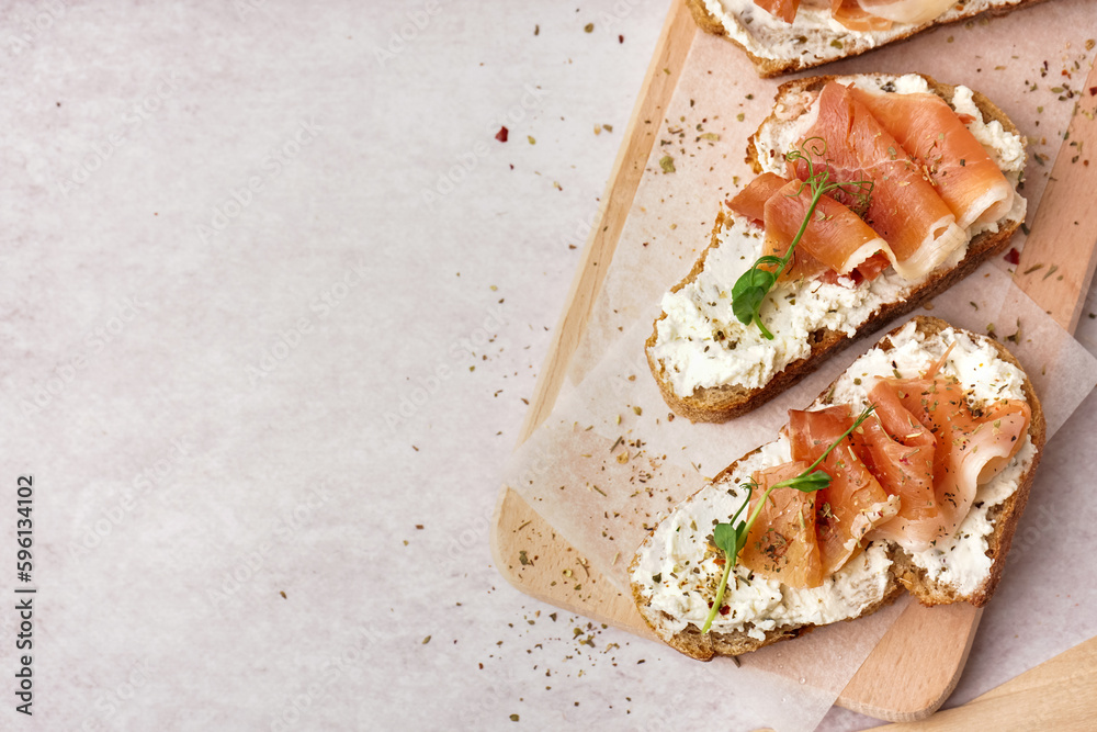 Wooden board of tasty bruschettas with jamon on white background