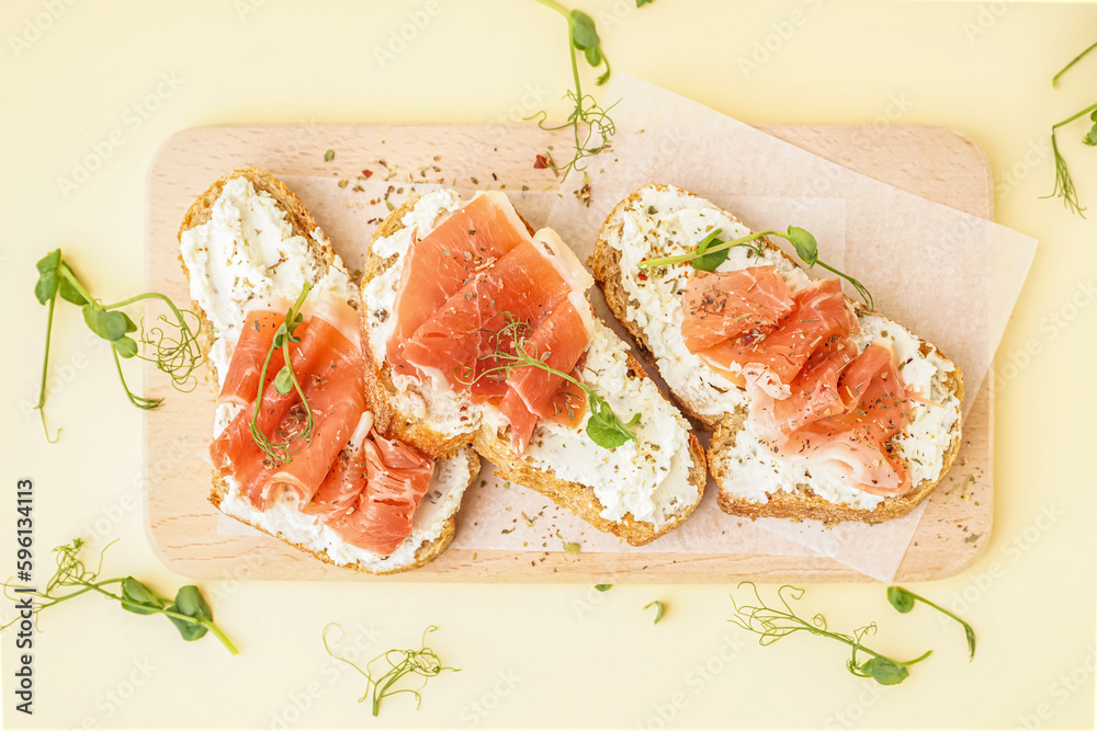 Wooden board of tasty bruschettas with jamon on beige background