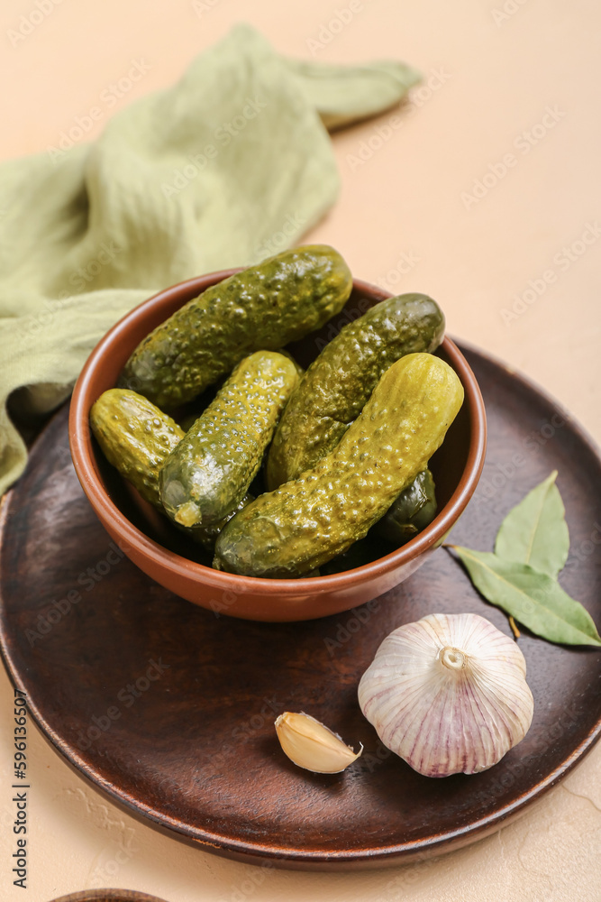 Bowl with tasty fermented cucumbers on beige background