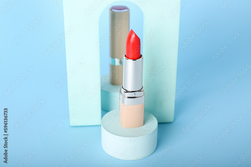 Decorative plaster podiums and lipstick on blue background