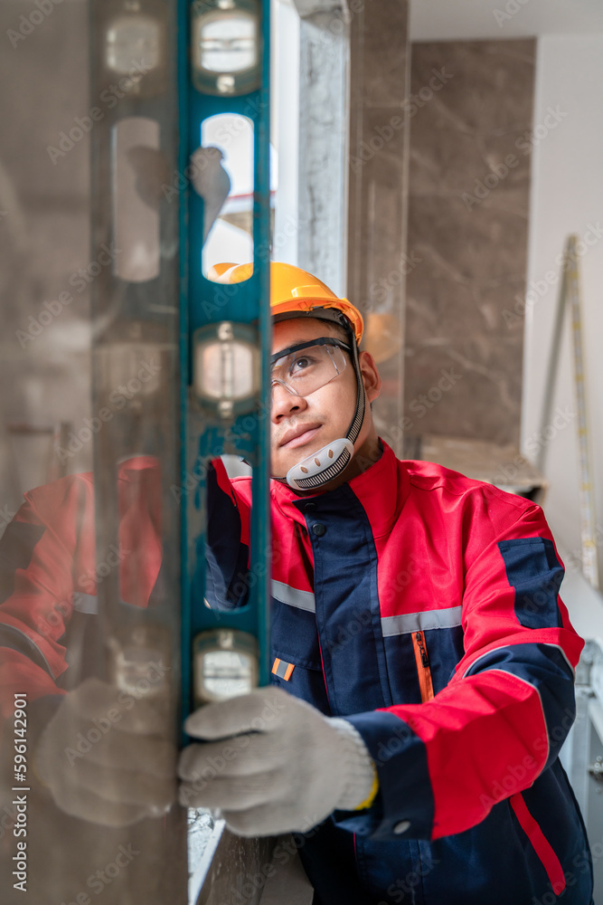 An engineer or inspector wearing a safety gear is inspecting a house by measuring the water level fo