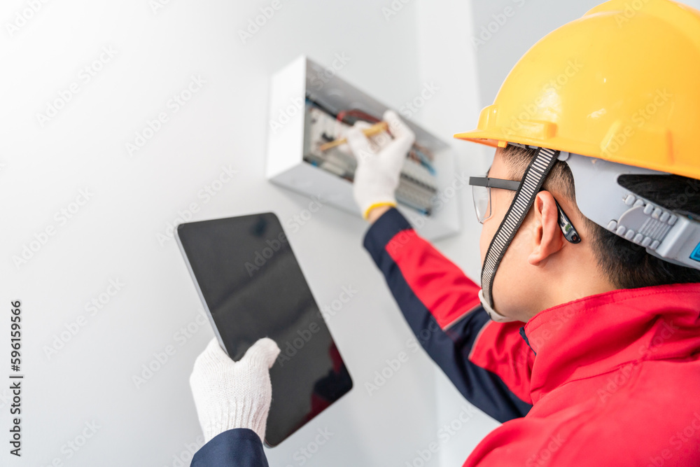 Asian electrician or engineer tester measuring voltage at fuse switch box in the house. Bay control 