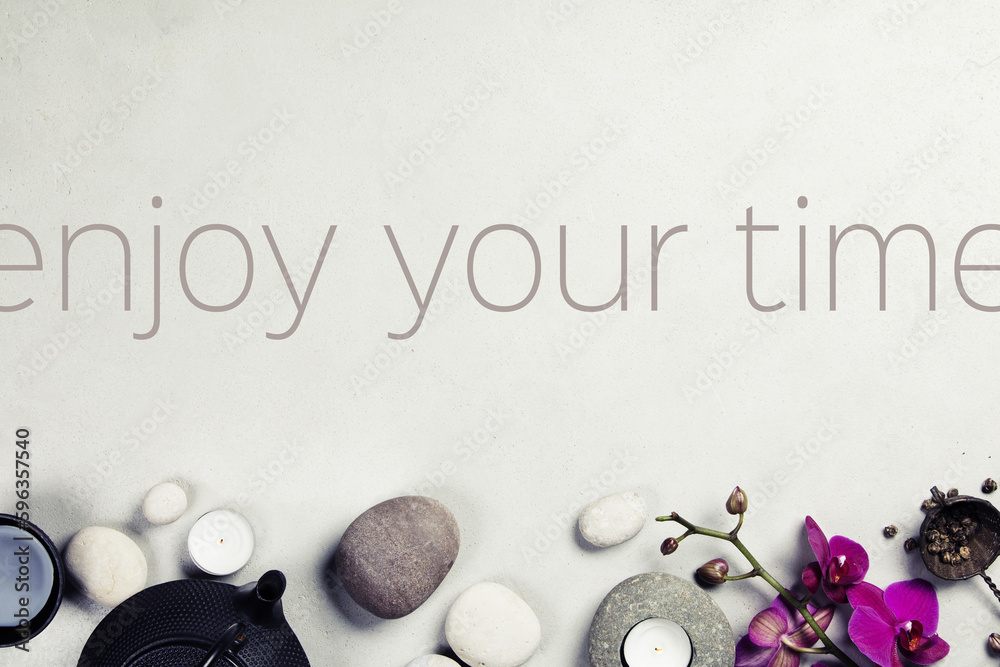 Inspirational quote Enjow your time . Asian tea set and spa stones on concrete background