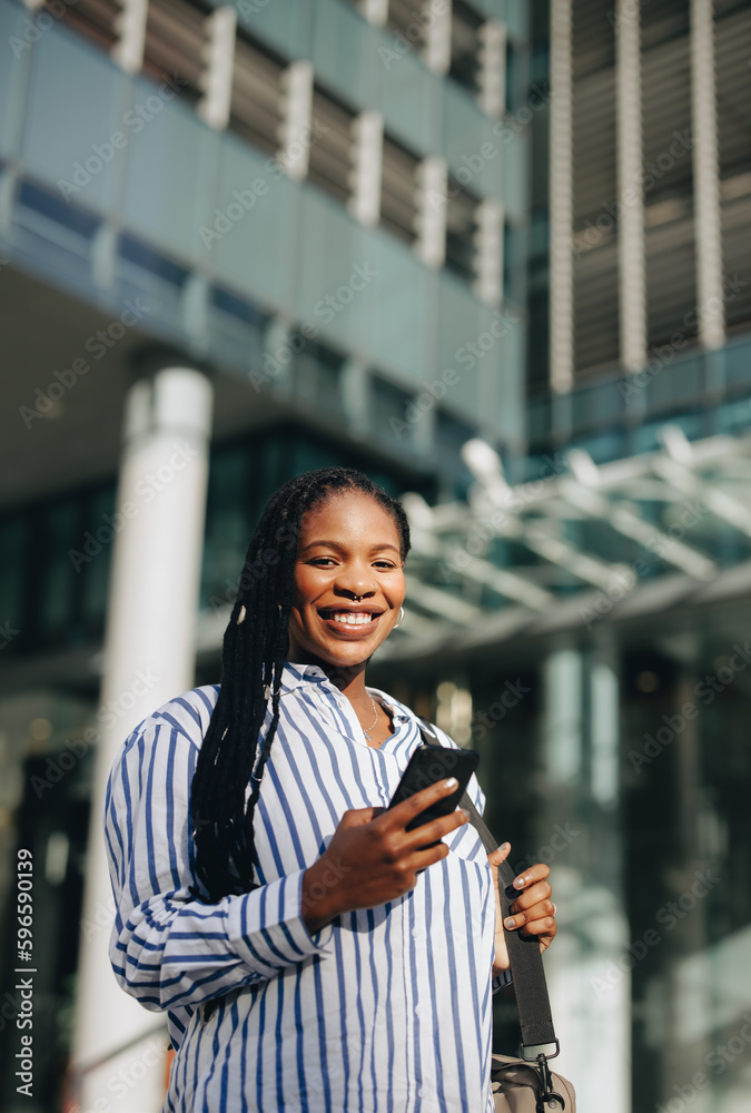 Happy black businesswoman smiling at the camera on her way to work in the city