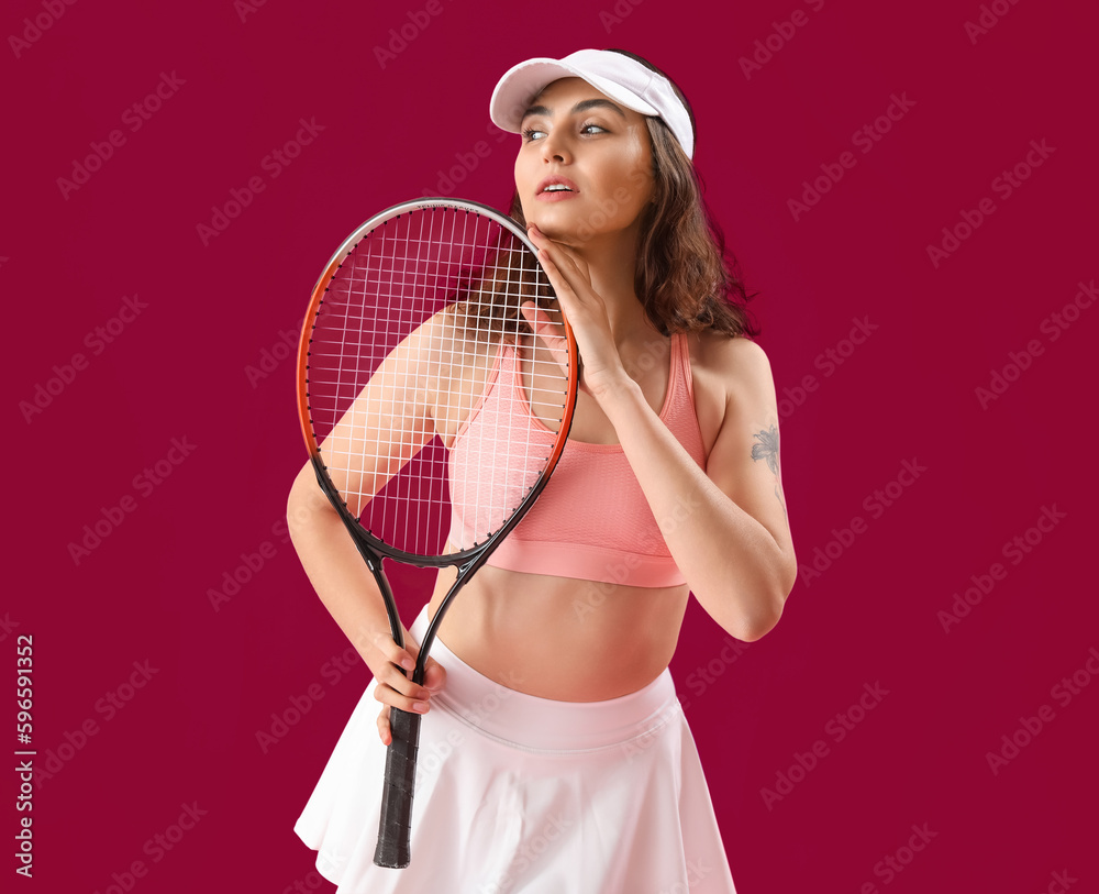 Young woman with tennis racket on pink background