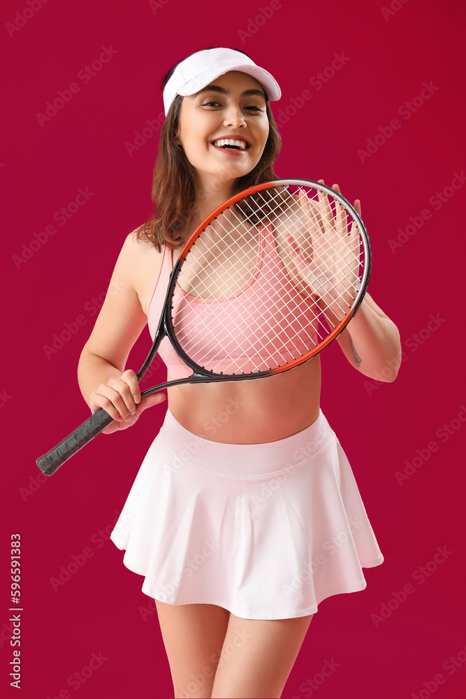 Young woman with tennis racket on pink background