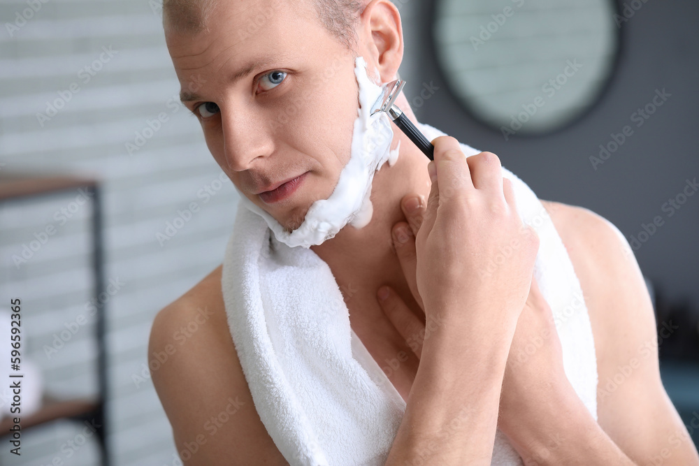 Young man shaving in bathroom