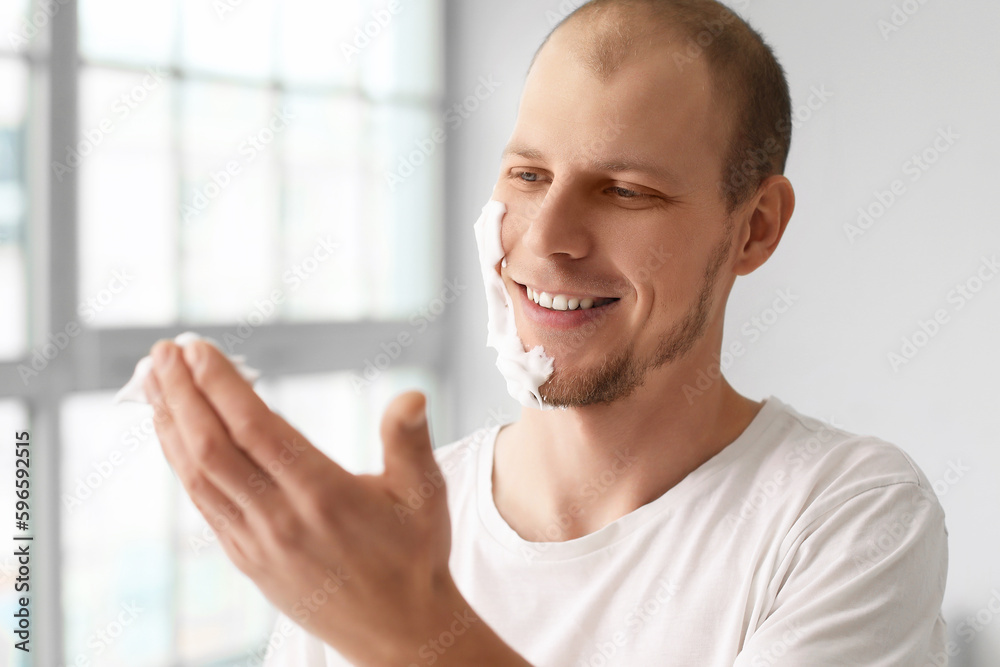 Young man shaving in bathroom