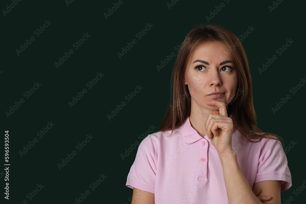 Thoughtful young woman in pink t-shirt on green background