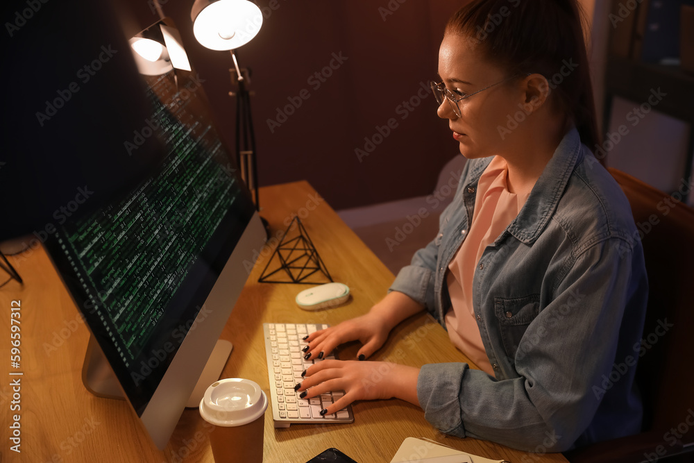 Female programmer working with computer in office at night